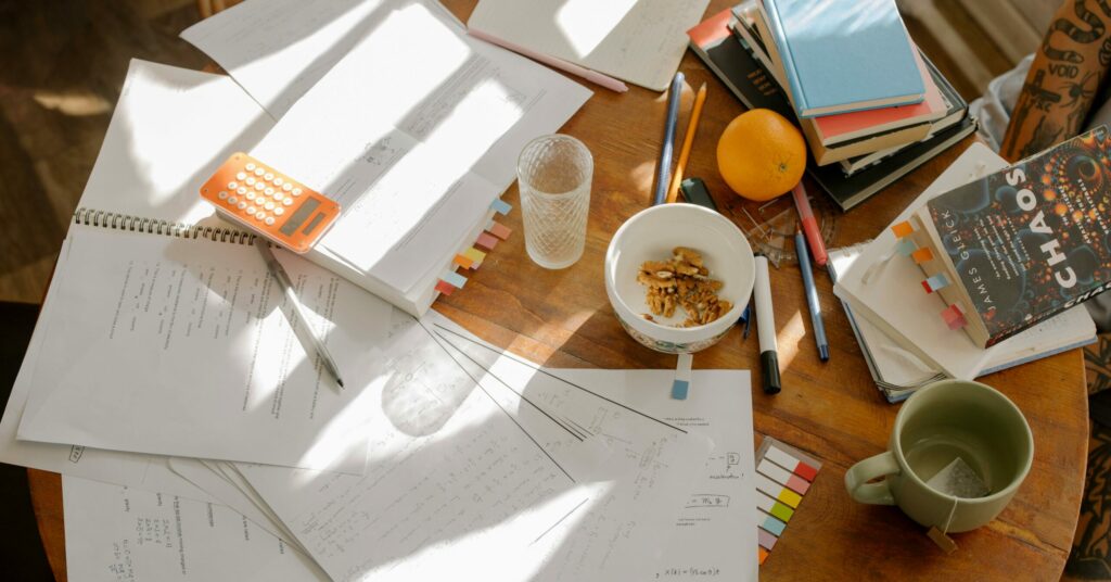 A cluttered study table with books, notes, and study materials in natural light for focused exam preparation.